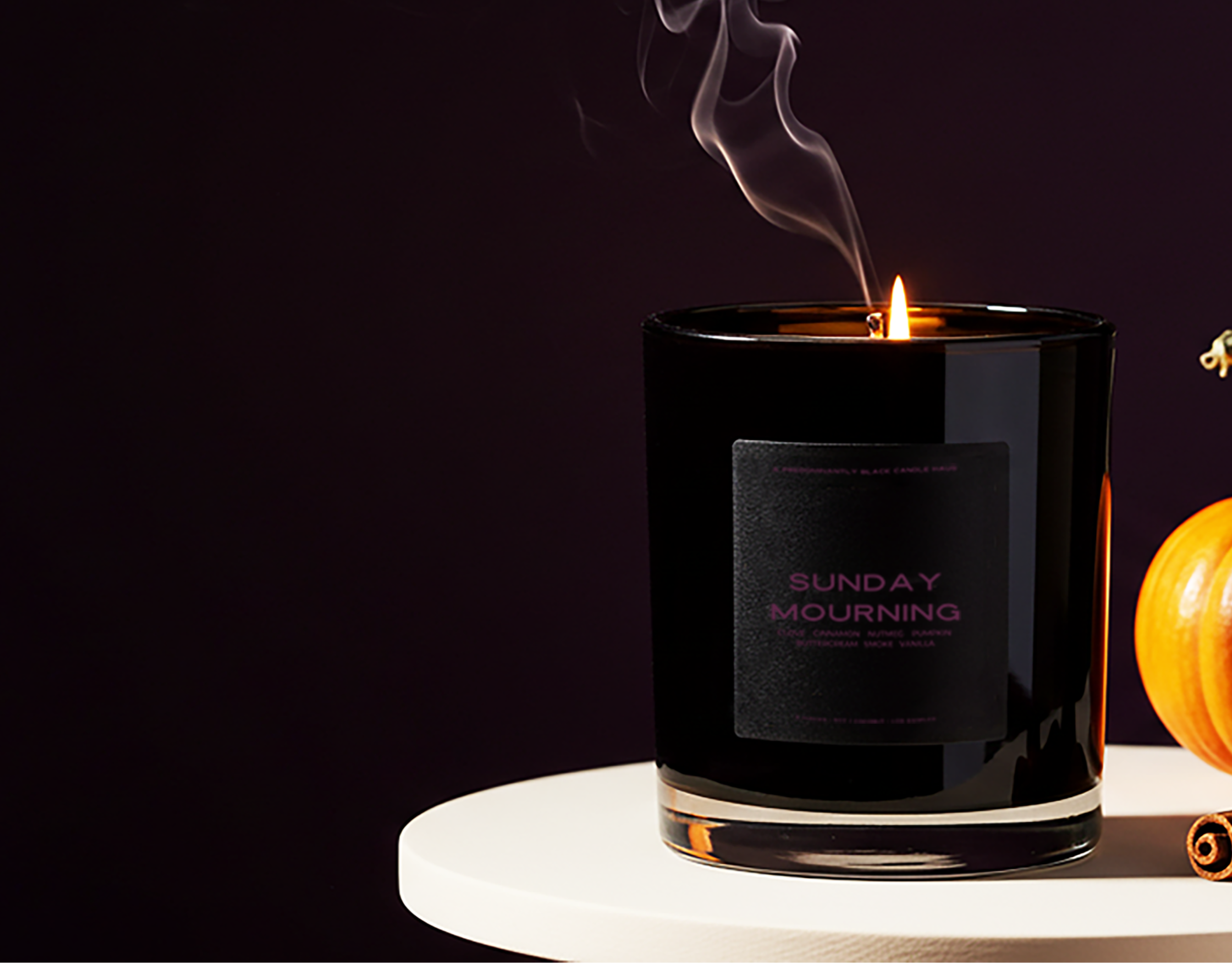 Black candle with smoke and a small pumpkin on a dark background