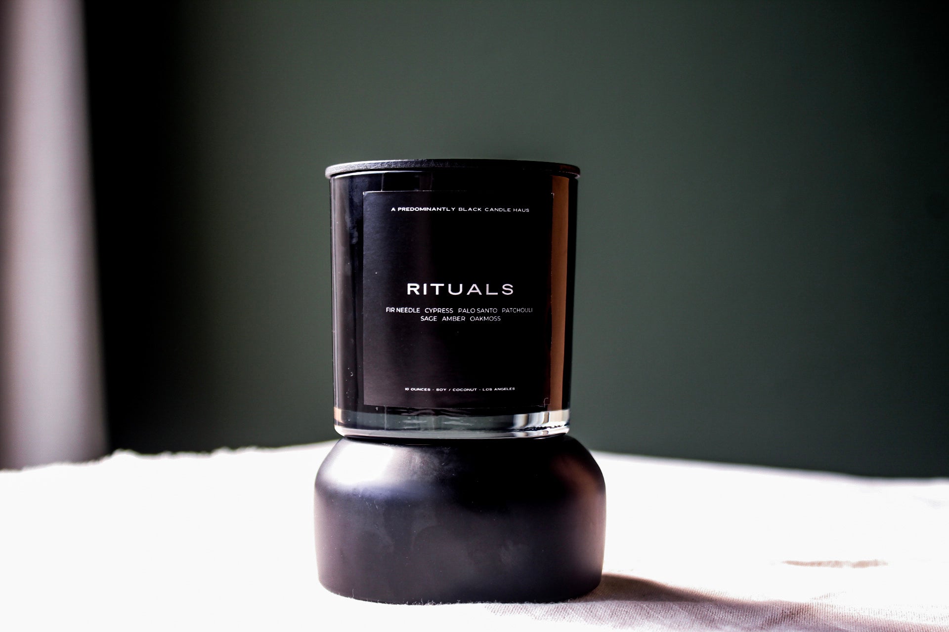 A Predominantly Black branded candle displayed against a predominantly black background, evoking an atmosphere of calm and serenity.