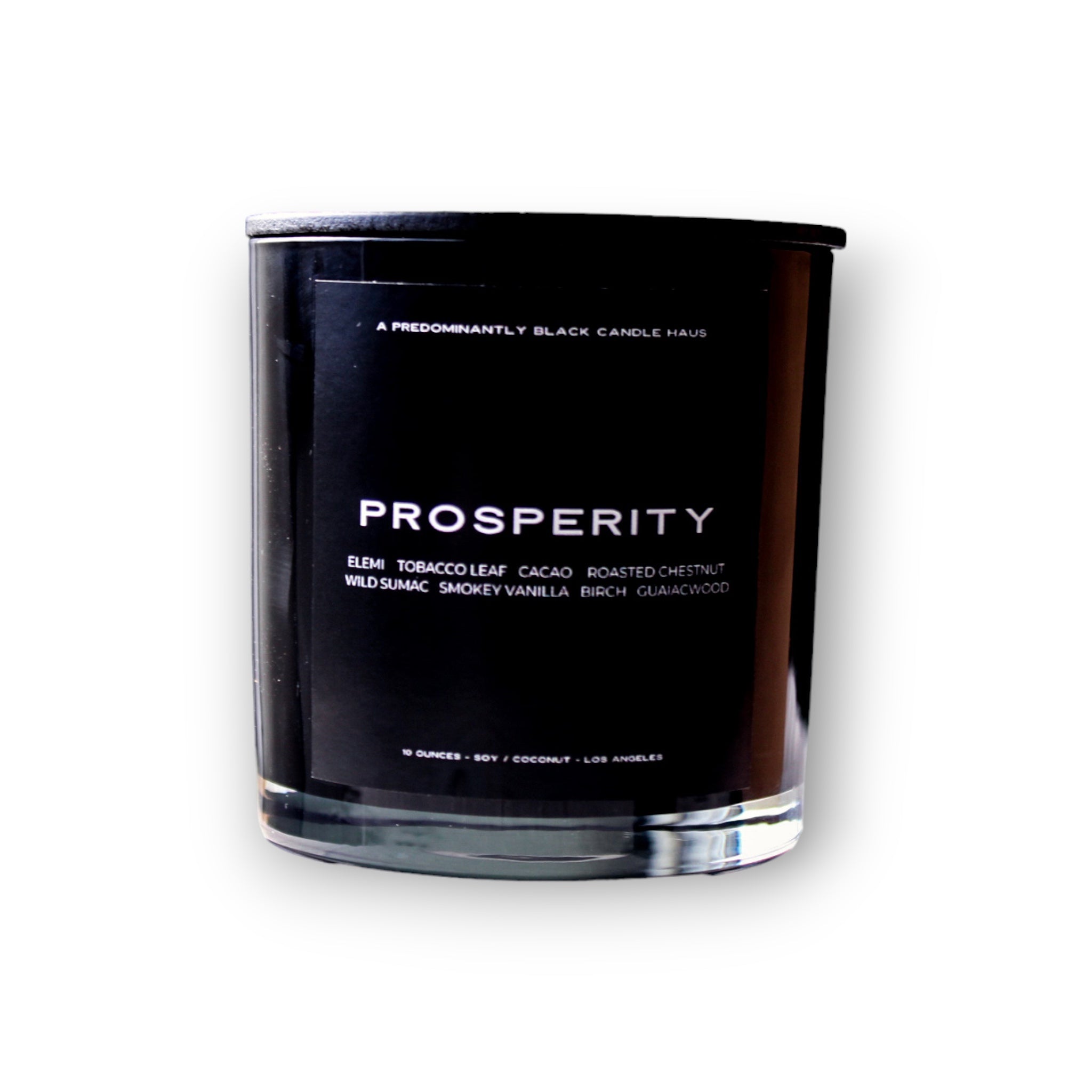 A Predominantly Black candle labeled "PROSPERITY" with scent notes, including tobacco leaf, cacao, roasted chestnut, wild sage, smoky vanilla, birch and oud wood.