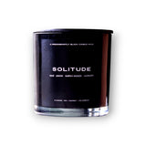 A sleek predominantly black SOLITUDE CANDLE labeled "solitude" with notes of sage, lemon, earthy woods, and lavender, presented against a clean white background.