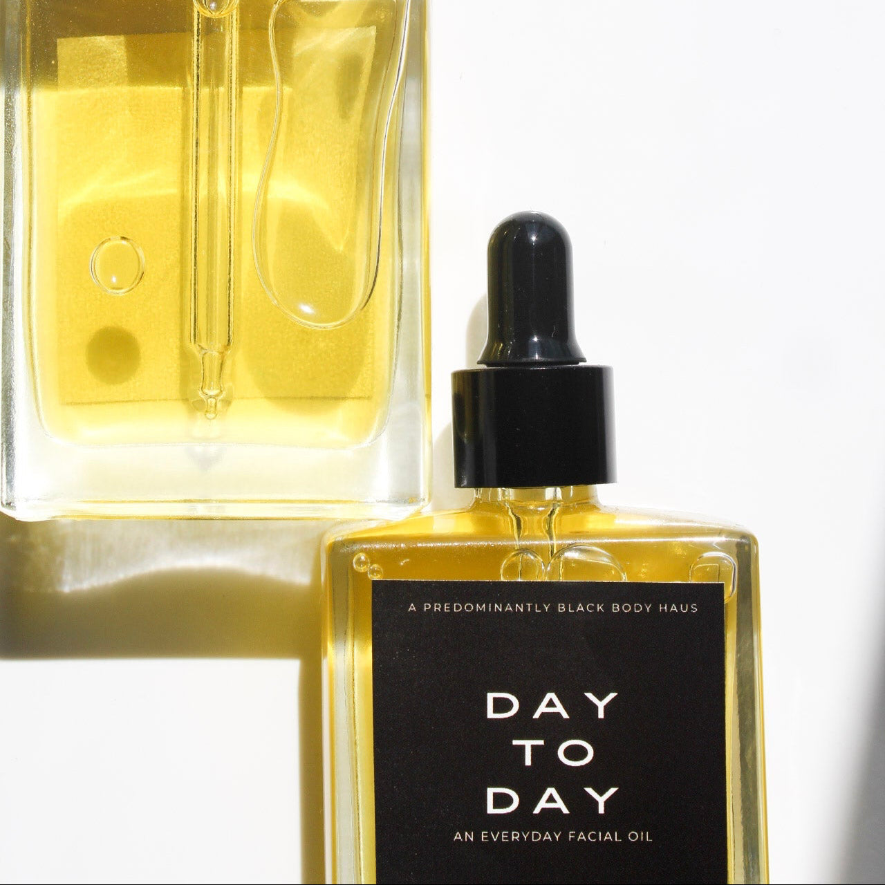 DAY-TO-DAY facial oil bottle and golden oil close-up — Predominantly Black
