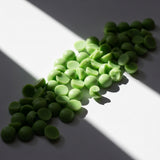 MADNESS Wax Melt: green scented wax melt pieces on white; fig and currant fragrance — Predominantly Black
