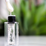 Open HAUS GLOSS bottle with applicator outdoors — Predominantly Black