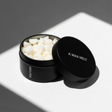 Open SOLITUDE scented wax melt tin with pale pieces; sage and lavender fragrance — Predominantly Black