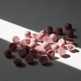 PATCHOULI + LINEN Wax Melt: pink scented wax melt pieces arranged in directional light; patchouli and linen fragrance — Predominantly Black