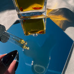 ROSEHIP FACIAL OIL bottle in a hand with shadows — Predominantly Black