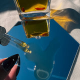 ROSEHIP FACIAL OIL bottle in a hand with shadows — Predominantly Black