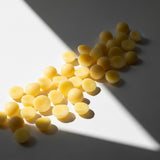 COCONUT HUSK + GINGER Wax Melt: yellow scented wax melt pieces on white; coconut husk and ginger fragrance — Predominantly Black