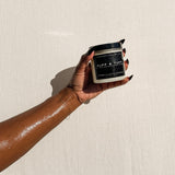 Hand holding a RUFF & TUFF exfoliating sugar body scrub jar — Predominantly Black